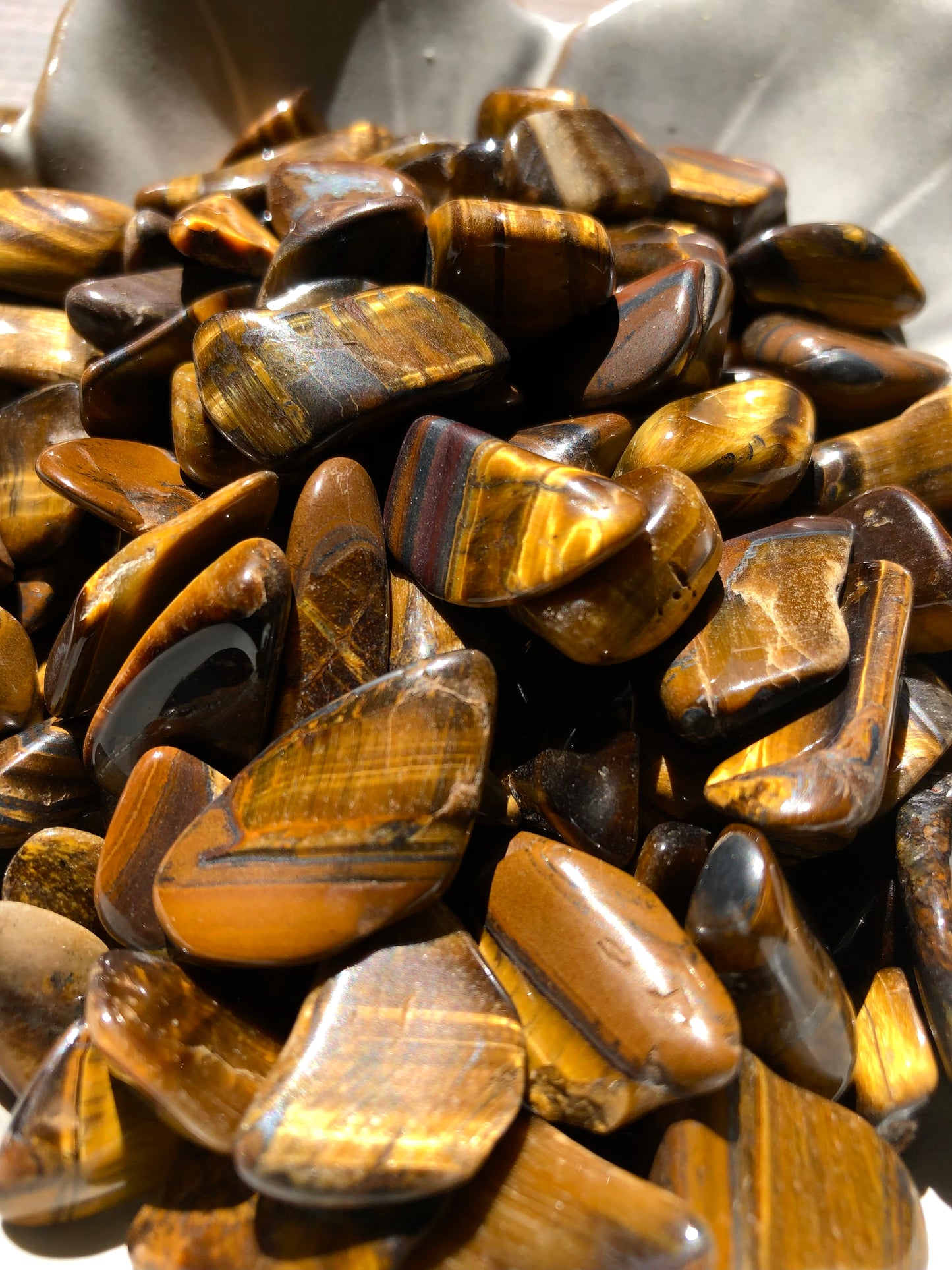 A close up picture of gold tiger eye stones. They are various hues of browns and golds.