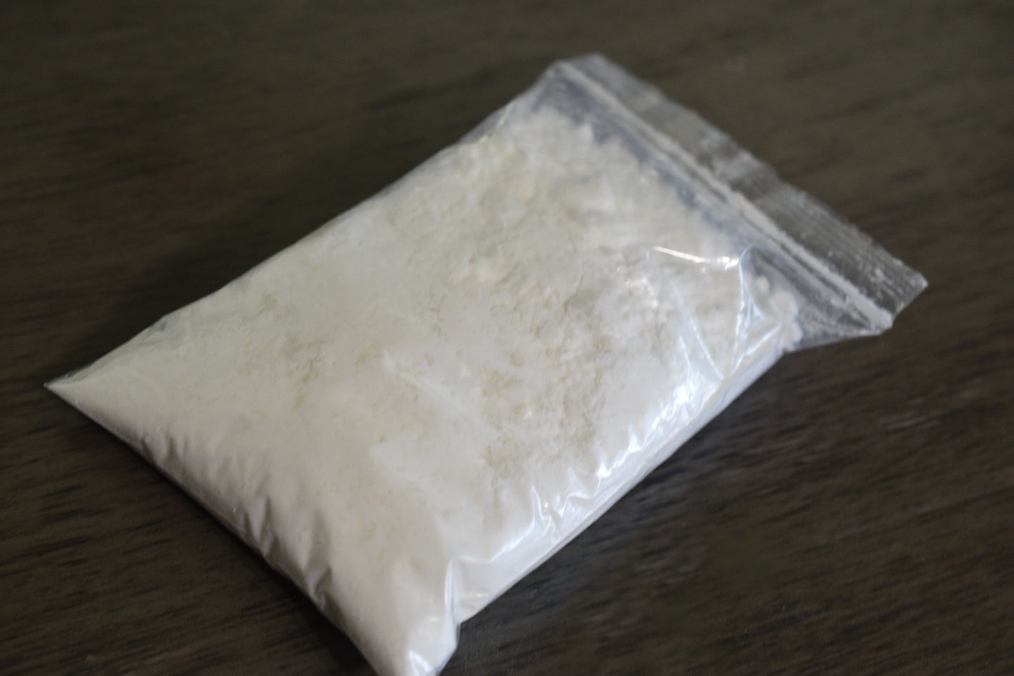 A plastic bag filled with coconut milk powder rests on a wooden surface to show the packaged product.