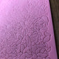 A close up view of a corner of the textured pink floral design mat on a wooden surface.