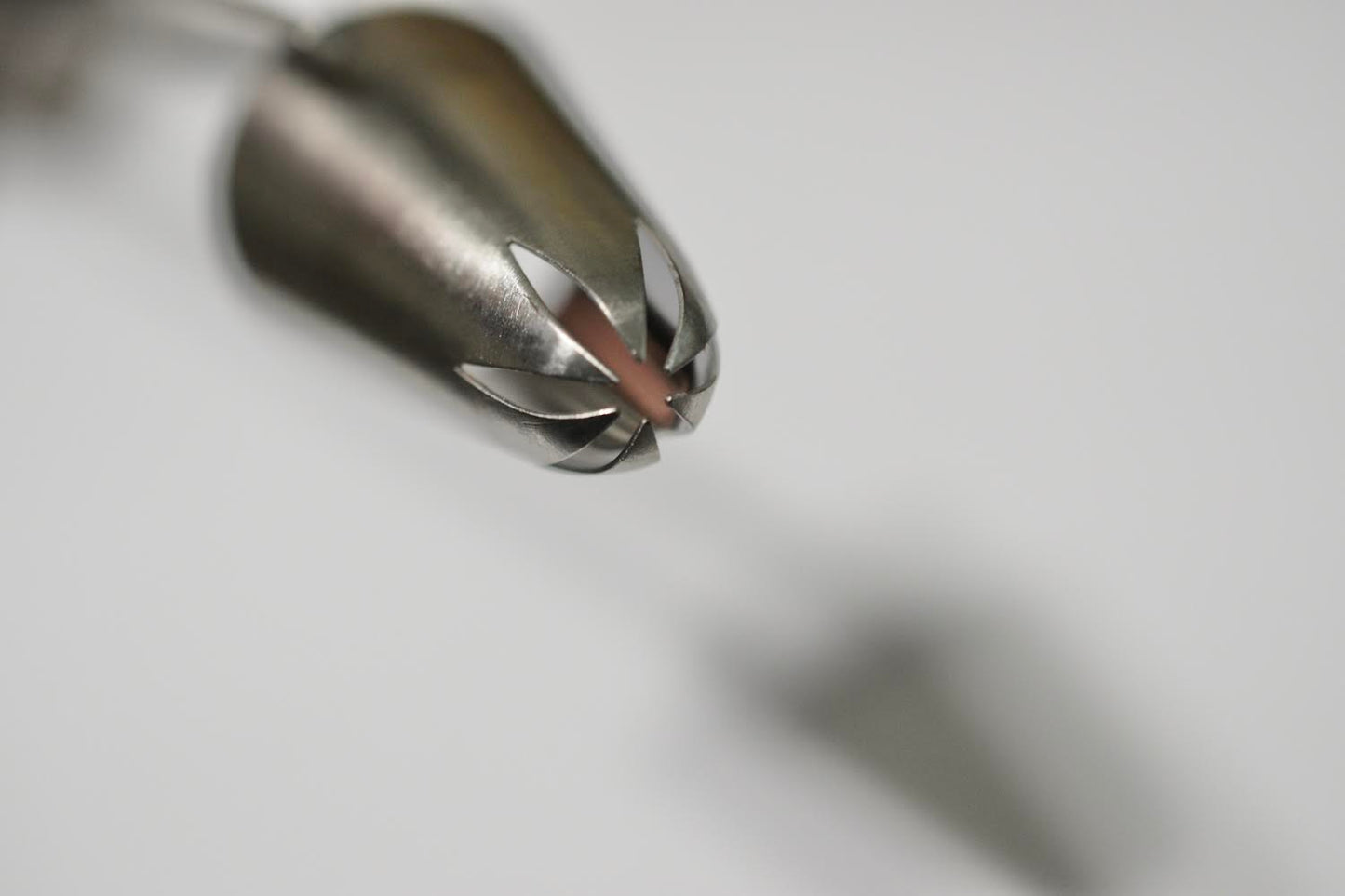 A metal piping tip with a closed star opening on one end. The other end is open. The piping tip is on its side. It is against a white background.