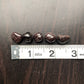 Five black garnet stones sit against a dark wood background. They are next to a white ruler showing each stone is approximately half an inch wide.