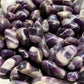 An up close picture of chevron banded amethyst stones. They are various hues of purple with swirls of white and cream colors.