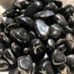 A close up picture of black onyx stones. They are shiny and dark black.