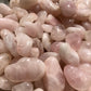 A close up picture of rose quartz stones. They are various hues of light pink and whites.