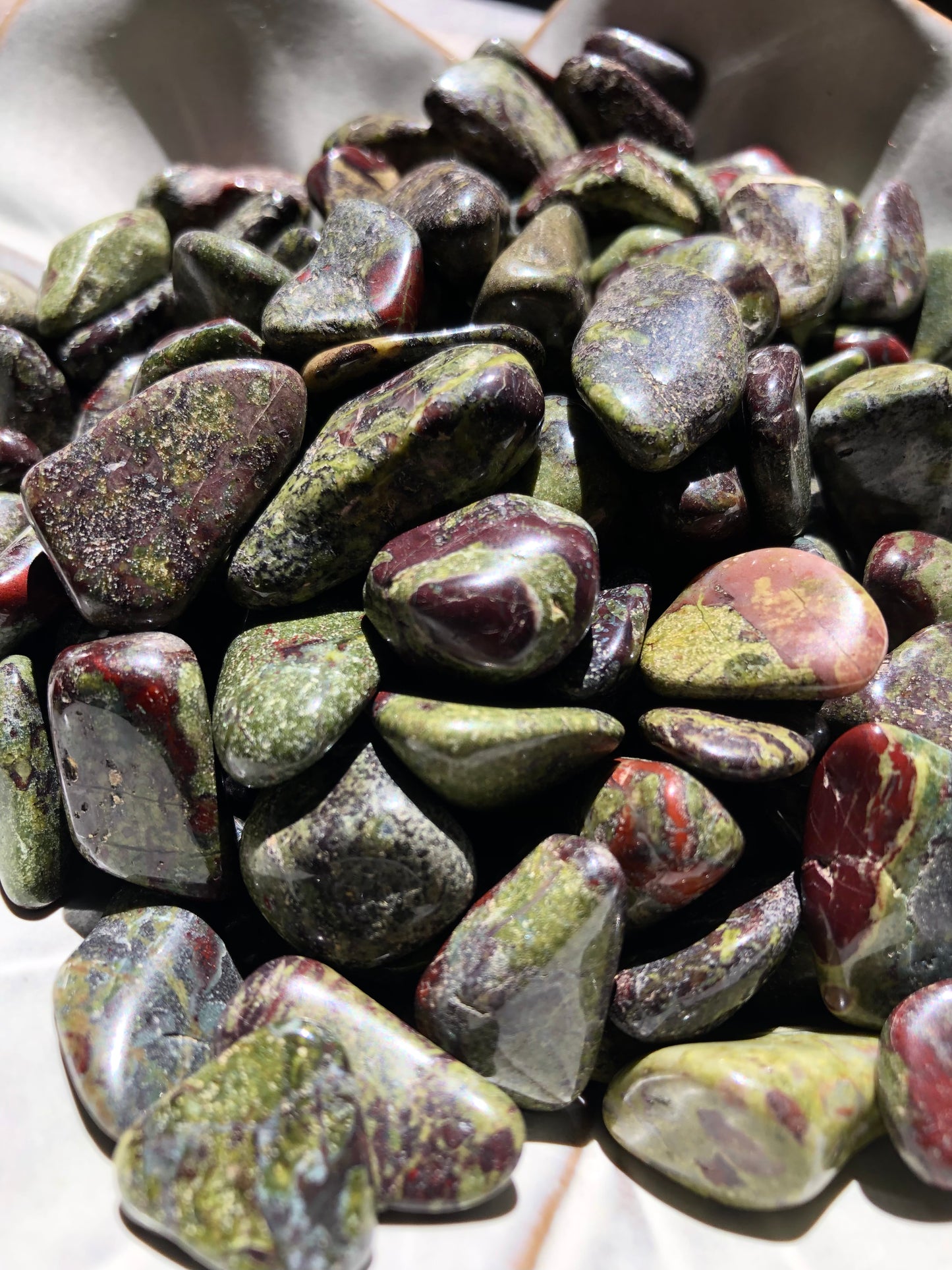 A close up picture of dragon's blood stones. They are various hues of dark purple, reds and greens.
