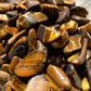 A close up picture of gold tiger eye stones. They are various hues of browns and golds.
