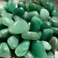 An up close picture of green adventurine stones. They are various hues of green.