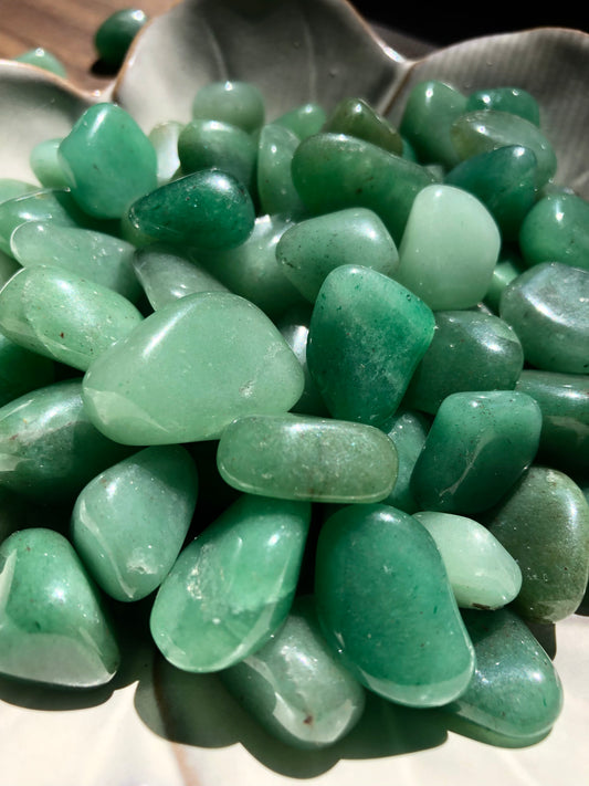 An up close picture of green adventurine stones. They are various hues of green.