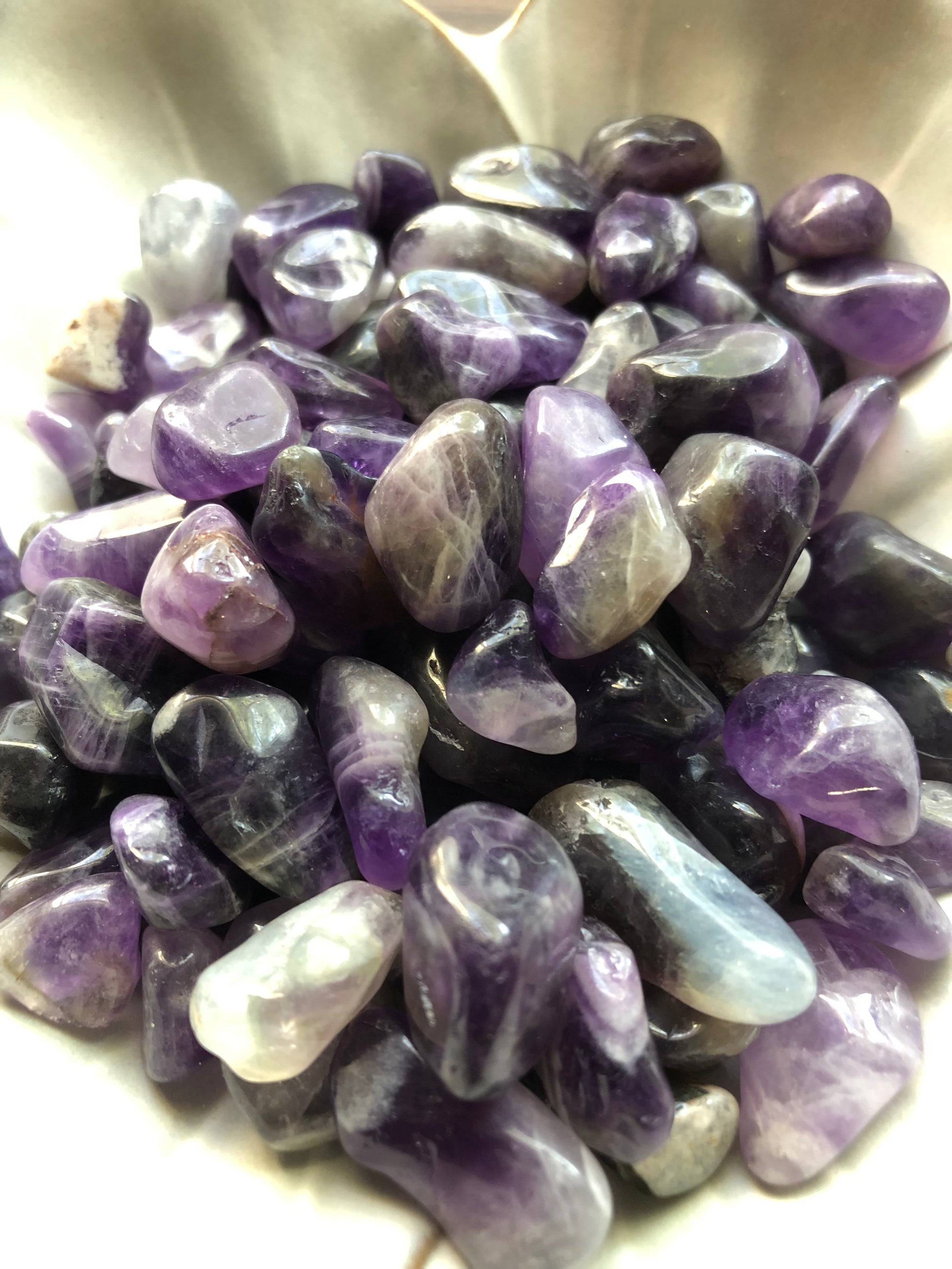 A close up picture of the tumbled amethysts sitting in a white bowl.