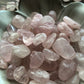 A close up picture of tumbled rose quartz sitting in a white bowl.