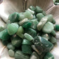 A close up picture of tumbled aventurine stones in a white bowl.