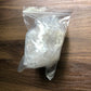 A plastic bag filled with quartz crystals of various sizes on a wooden surface, which are wrapped in bubble wrap to show the packaged product.
