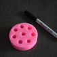 A top view of the black berry mold. It is next to a sharpie pen for size comparison. The sharpie is moderately longer than the mold in length. The soap mold is pink.