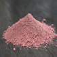 A close up view of a pile of rose clay rests on wooden surface. The clay is a light pink color.