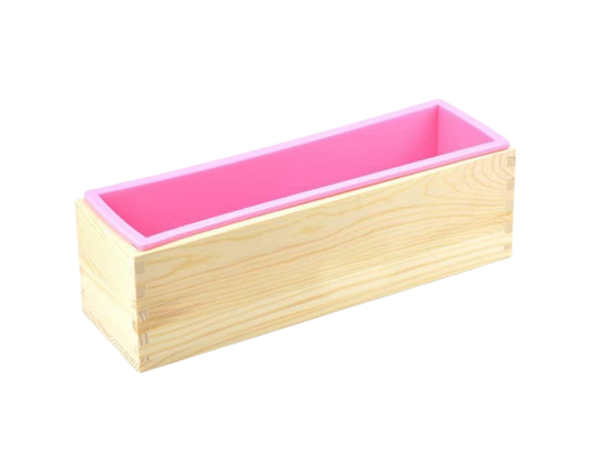 A loaf shaped wood box houses a pink silicone mold inside. It is against a transparent background. The wood of the mold is light in color.