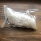 A plastic bag filled with quartz crystals of various sizes on a wooden surface, which are wrapped in bubble wrap to show the packaged product.