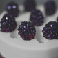 A close up view of the black berry mold, showing completed soap black berries. The soap blackberries have been colored a dark purple. The soap mold is grey.