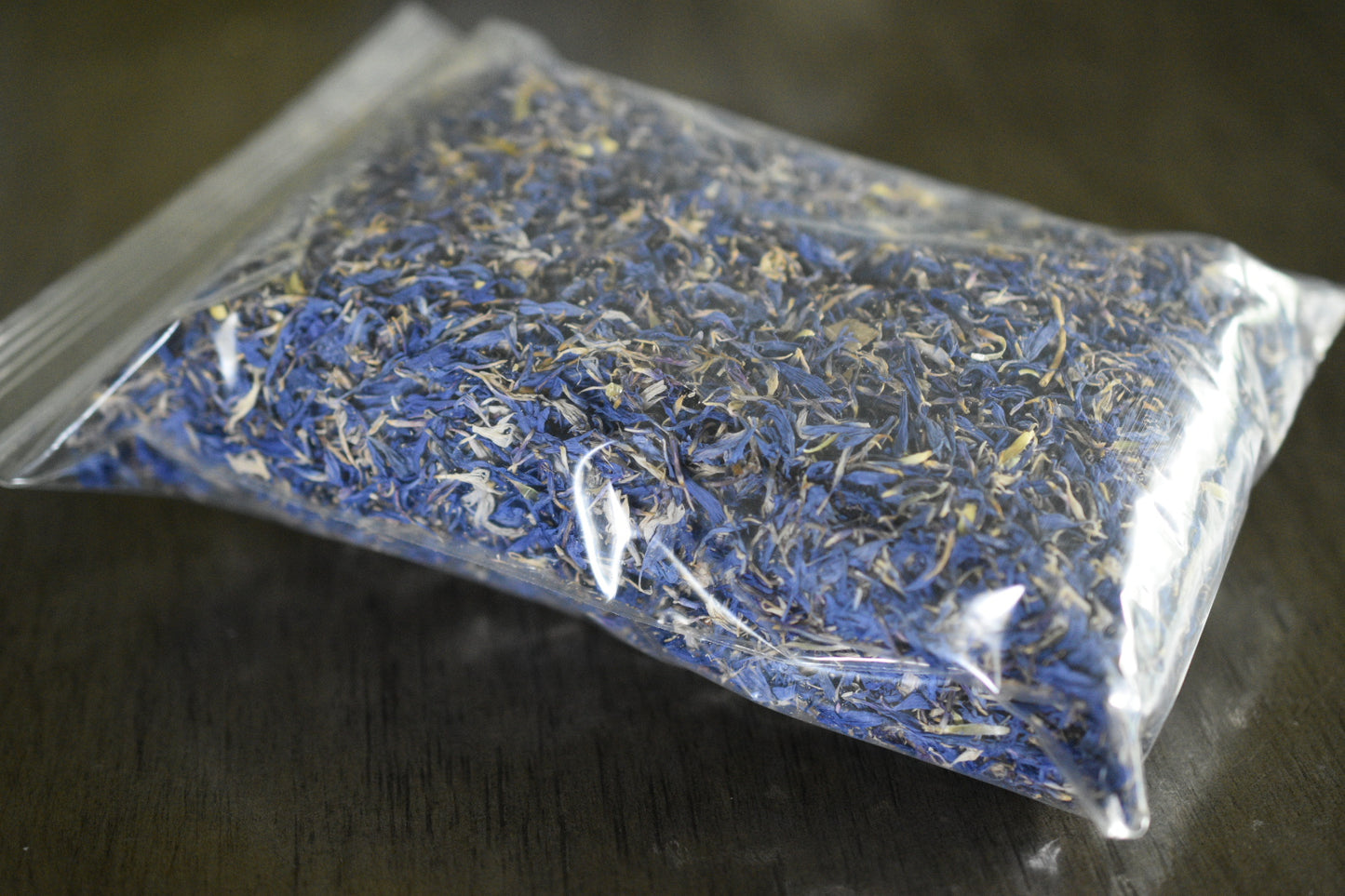 A close up view of 1 ounce of packaged blue cornflowers in a plastic bag with no label.